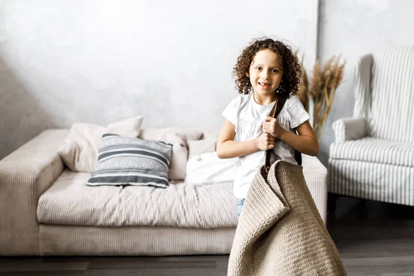 Uma menina bonita com cabelo encaracolado mantém um enorme saco de malha — Fotografia de Stock