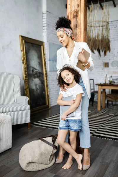 Uma linda mãe e filha conversam e olham para o tablet enquanto estão na sala de estar — Fotografia de Stock