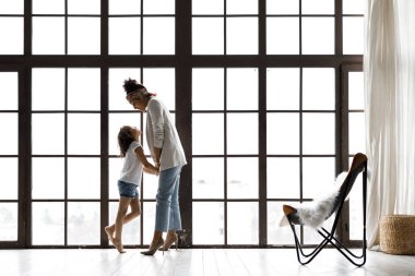 Pencere tarafından kucaklayan sevgi dolu anne ve kızı yan görünümü