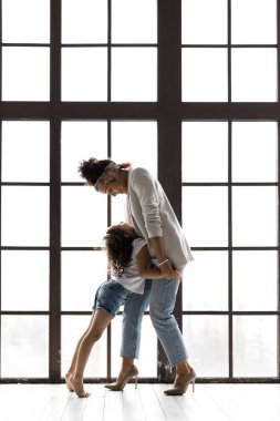 Pencere tarafından kucaklayan sevgi dolu anne ve kızı yan görünümü