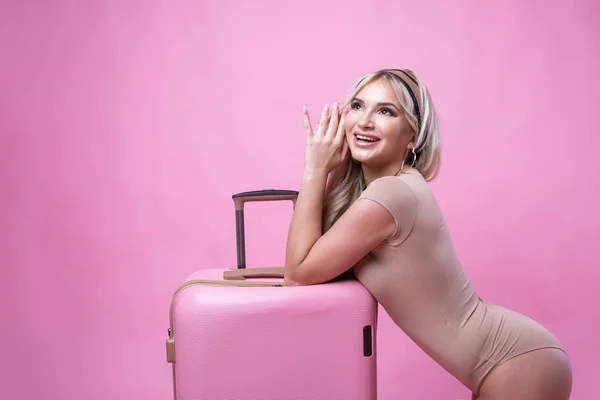 Young pretty girl blonde posing on pink background with suitcase — Φωτογραφία Αρχείου