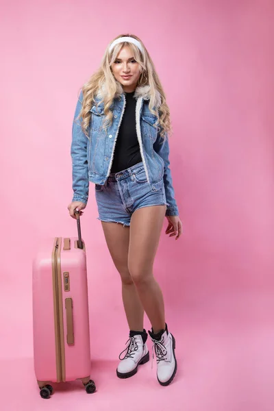 Linda chica sexy - rubia con maleta rosa de pie sobre fondo rosa — Foto de Stock