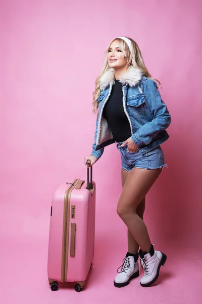 Linda chica sexy - rubia con maleta rosa de pie sobre fondo rosa — Foto de Stock