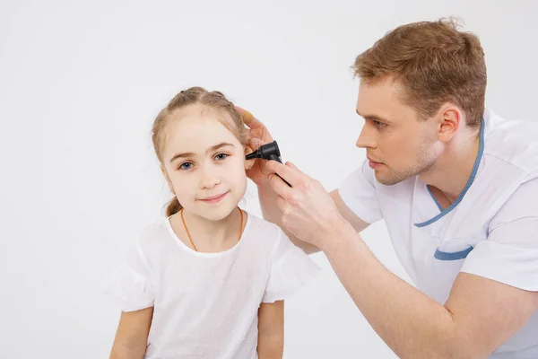 The young sympathetic otolaryngologist examines the ears of a girl - a girl of school age. People isolated on a white background — Stock Photo, Image