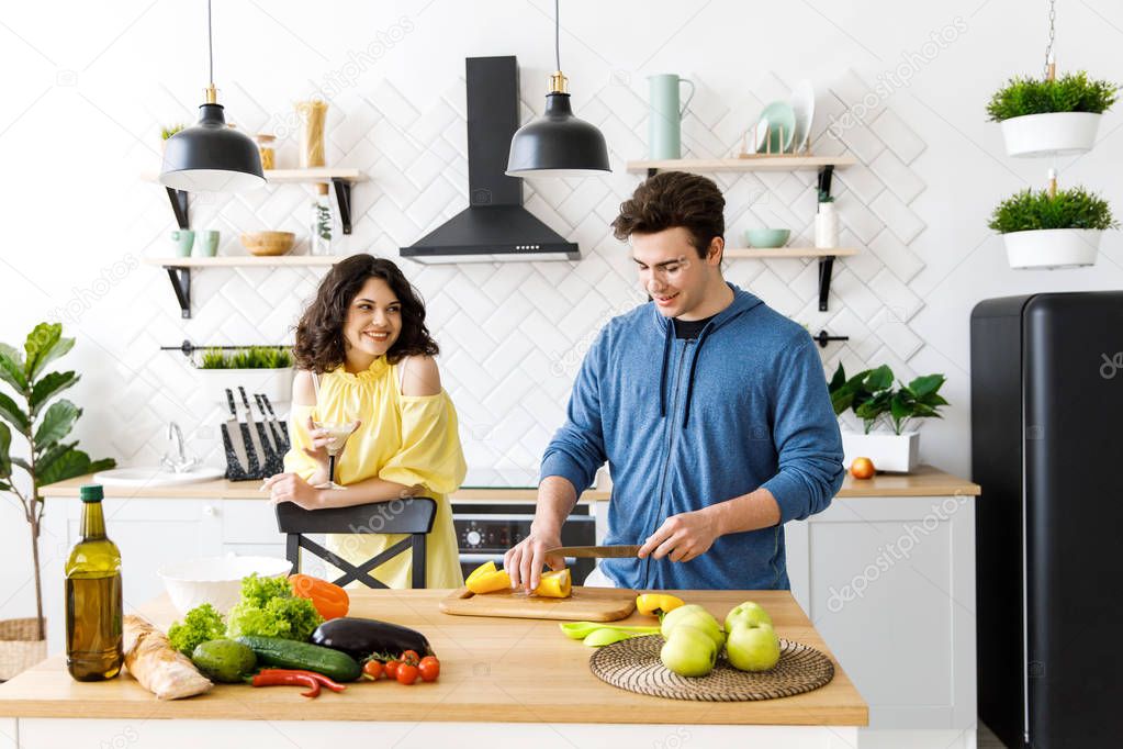 Young cute smiling couple cooking together at kitchen at home. A couple - a girl and a boy who spend time together for cooking