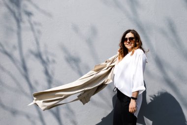 Genç, sempatik bir kadın, ince başlı bir vücut bina değil, duvarın arka planda duruyor. İş giyim tarzı.