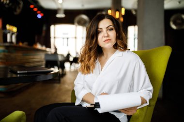 Ön manzara. Genç bir kadın kafede oturuyor, elinde kalem tutuyor, belgeleri okuyor. Bir iş kadını sözleşme imzalar. Girişimci, girişimci çalışıyor.