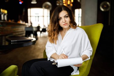 Ön manzara. Genç bir kadın kafede oturuyor, elinde kalem tutuyor, belgeleri okuyor. Bir iş kadını sözleşme imzalar. Girişimci, girişimci çalışıyor.