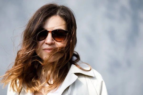 Genç, sempatik bir kadın, ince başlı bir vücut bina değil, duvarın arka planda duruyor. İş giyim tarzı.