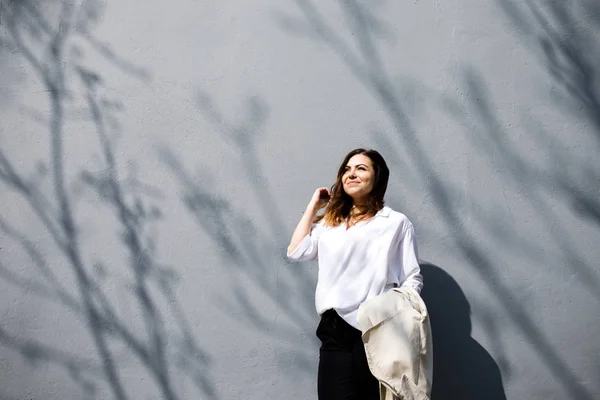 Une jeune femme sympathique, pas une musculation à la tête fine, se tient sur le fond du mur. Style de vêtements d'affaires . — Photo