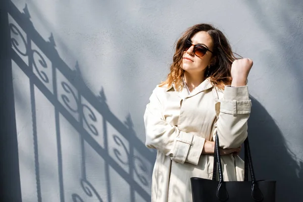 A young, sympathetic woman, not a thin-headed body building, stands on the background of the wall. Business clothing style.