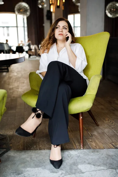 Güzel gülümseyen genç kadın kafede sandalyede oturan elbise giymiş, cep telefonu, şık iç konuşma