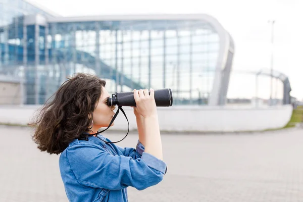 Young pretty girl looks away with a binocular in her hands. The young man travels — 스톡 사진