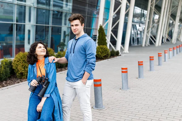 Jovem casal bonito - um menino e uma menina andando pela cidade com um binocular em suas mãos. Jovens viajam . — Fotografia de Stock