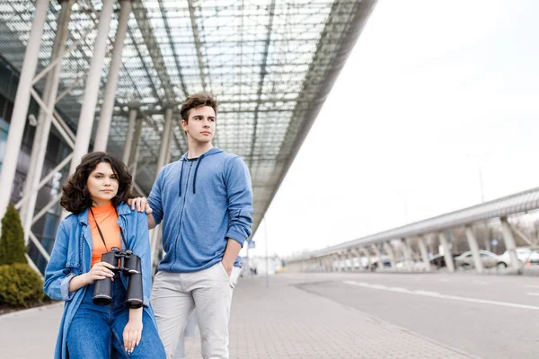 Jovem casal bonito - um menino e uma menina andando pela cidade com um binocular em suas mãos. Jovens viajam . — Fotografia de Stock