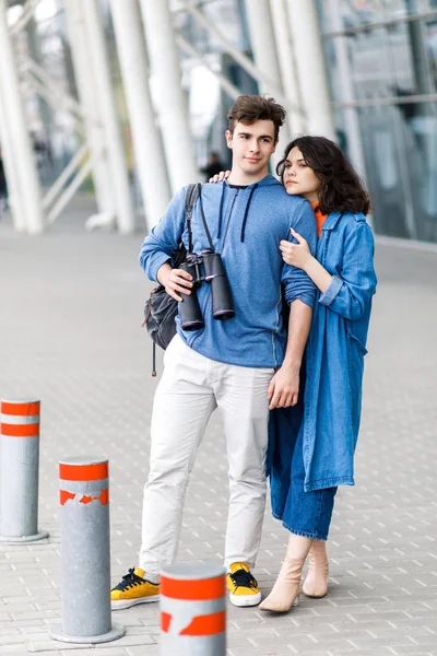 Ένα νεαρό όμορφο ζευγάρι - ένα αγόρι και ένα κορίτσι που περπατούν στην πόλη με ένα κιάλια στα χέρια του. Οι νέοι ταξιδεύουν. — Φωτογραφία Αρχείου