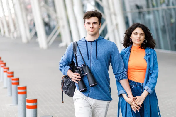 Jovem casal bonito - um menino e uma menina andando pela cidade com um binocular em suas mãos. Jovens viajam . — Fotografia de Stock