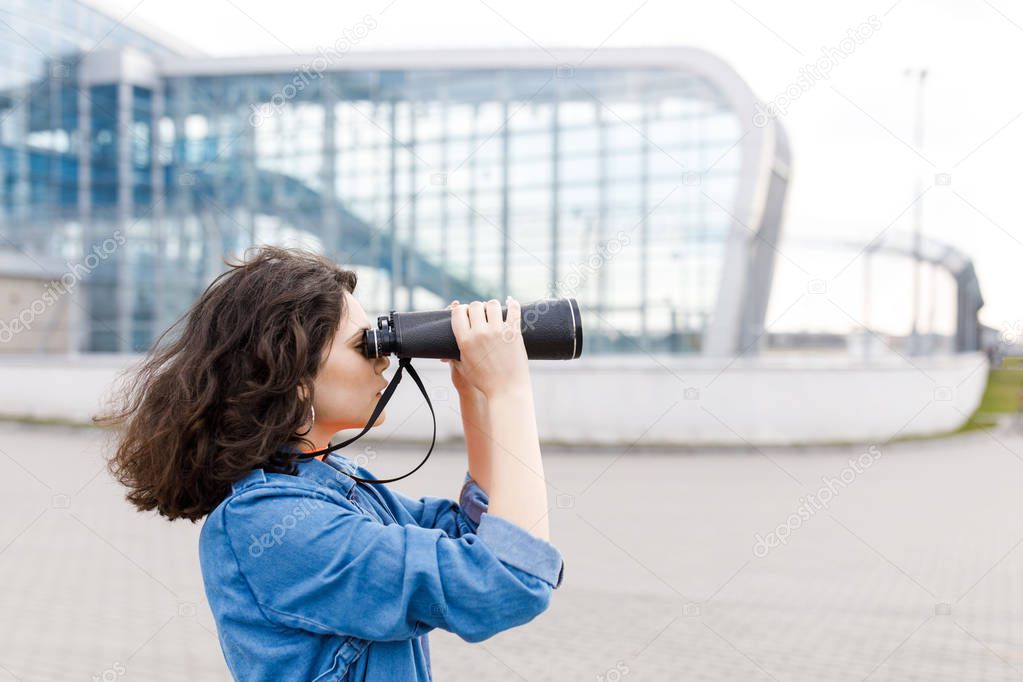 Young pretty girl looks away with a binocular in her hands. The young man travels