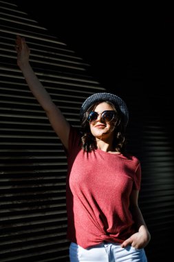 Young pretty brunette walking around the city on a sunny day, dressed in summer clothes, and a hat on her head. Summer style