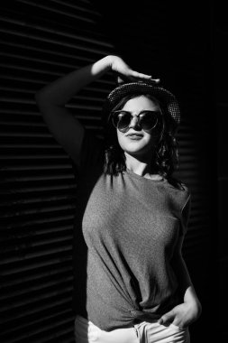 Young pretty brunette walking around the city on a sunny day, dressed in summer clothes, and a hat on her head. Summer style