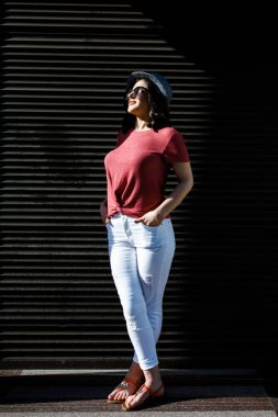 Young pretty brunette walking around the city on a sunny day, dressed in summer clothes, and a hat on her head. Summer style
