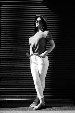 Young pretty brunette walking around the city on a sunny day, dressed in summer clothes, and a hat on her head. Summer style