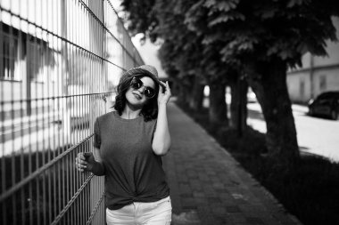 Young pretty brunette walking around the city on a sunny day, dressed in summer clothes, and a hat on her head. Summer style