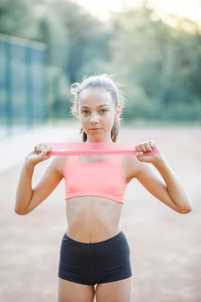 Una joven y simpática chica de cuerpo delgado, vestida con una forma de  deporte, realiza ejercicios gimnásticos al aire libre