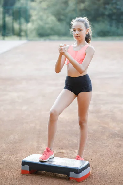 Ein nettes, hübsches Teenager-Mädchen führt verschiedene Outdoor-Übungen durch — Stockfoto