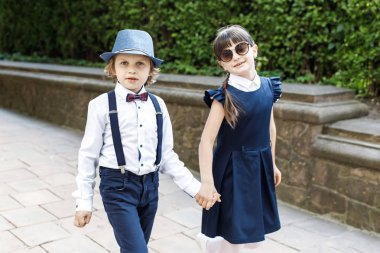 Sevimli sarışın adam ve sevimli kız, okul yılı eğlenceli zaman açık havada. Okul üniforması giymiş çocuklar parkta oyun oynar