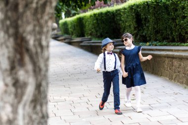 Sevimli sarışın adam ve sevimli kız, okul yılı eğlenceli zaman açık havada. Okul üniforması giymiş çocuklar parkta oyun oynar