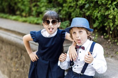 Sevimli sarışın adam ve sevimli kız, okul yılı eğlenceli zaman açık havada. Okul üniforması giymiş çocuklar parkta oyun oynar