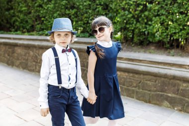 Sevimli sarışın adam ve sevimli kız, okul yılı eğlenceli zaman açık havada. Okul üniforması giymiş çocuklar parkta oyun oynar