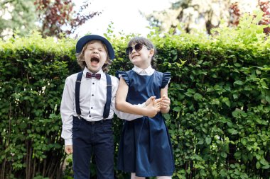 Sevimli sarışın adam ve sevimli kız, okul yılı eğlenceli zaman açık havada. Okul üniforması giymiş çocuklar parkta oyun oynar