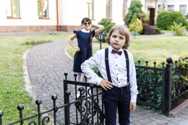 Sevimli sarışın adam ve sevimli kız, okul yılı eğlenceli zaman açık havada. Okul üniforması giymiş çocuklar parkta oyun oynar