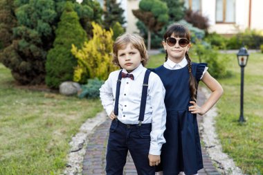 Sevimli sarışın adam ve sevimli kız, okul yılı eğlenceli zaman açık havada. Okul üniforması giymiş çocuklar parkta oyun oynar