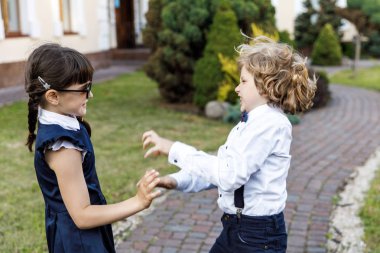 Sevimli sarışın adam ve sevimli kız, okul yılı eğlenceli zaman açık havada. Okul üniforması giymiş çocuklar parkta oyun oynar