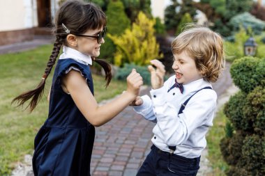 Sevimli sarışın adam ve sevimli kız, okul yılı eğlenceli zaman açık havada. Okul üniforması giymiş çocuklar parkta oyun oynar