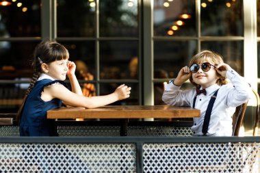 Sevimli sarışın adam ve güzel kız, okul yıl, okul üniforması giymiş, sokakta yaz kafede onu zaman harcıyor.