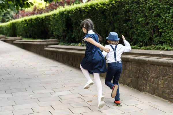Cute blond guy and cute girl, school year fun time outdoors. Children dressed in school uniform play games in the park