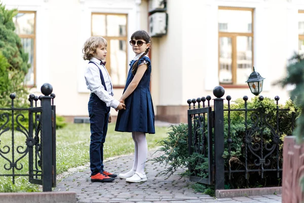 Chico rubio lindo y chica linda, diversión del año escolar al aire libre. Niños vestidos con uniforme escolar juegan juegos en el parque — Foto de Stock