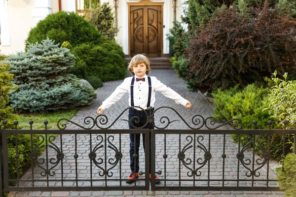 Bonito loiro, ano letivo, vestido de uniforme escolar, leva seu tempo ao ar livre entre as aulas. O tipo volta à escola outra vez. — Fotografia de Stock