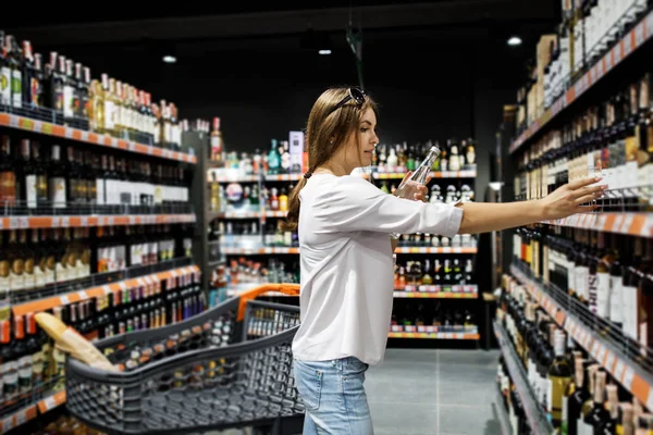 Genç güzel kız büyük bir mağazada alışveriş. Kız süpermarketten alışveriş yapıyor. Kız içecekler seçer