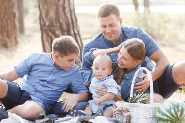 Beautiful happy family - parents and two sons, spend time in nature, laughing, eating fresh fruits and enjoying life — Stock Photo, Image
