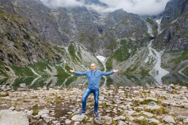 Genç, güçlü bir adam gölün yanındaki dağlarda duruyor. Sihirli manzara