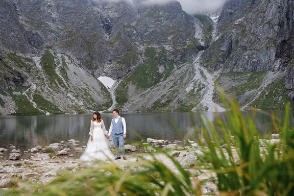 湖の近くの山の中でかわいい若い愛情のカップルの時間を過ごす。新婚夫婦二人で一人で歩く。新婚旅行 — ストック写真