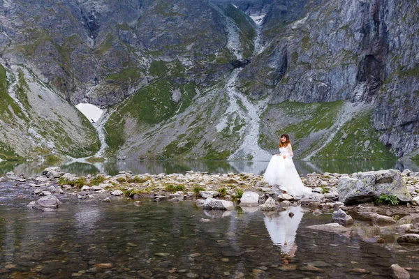 Piękna młoda kobieta spędzająca czas w górach nad jeziorem. Panna młoda podchodzi. miesiąc miodowy — Zdjęcie stockowe