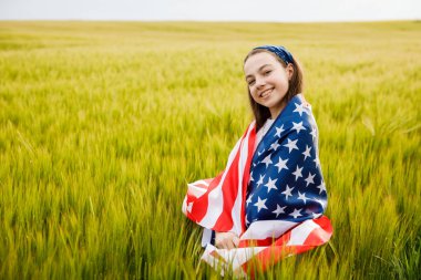 Tasasız güzel kız yeşil alanda koşuyor ve gülümsüyor ABD bayrağıyla.