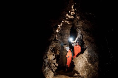Güçlü fiziği olan iki adam mağarayı keşfeder. Mağaradan geçmek için özel giyinmiş adamlar durup haritaya baktılar.