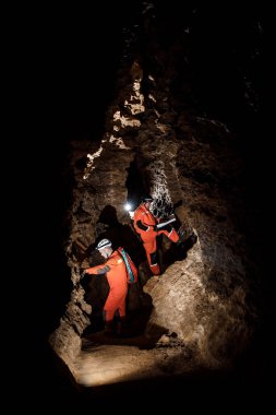 Güçlü fiziği olan iki adam mağarayı keşfeder. Mağaradan geçmek için özel giyinmiş adamlar durup haritaya baktılar.